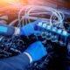 A man in blue gloves holds a bottle of oil, demonstrating how to improve fuel efficiency with a new diesel injector.